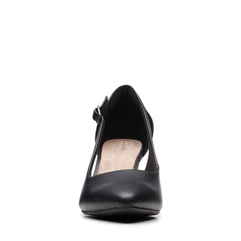 Close-up of a black leather shoe with a pointed toe and side buckle strap.