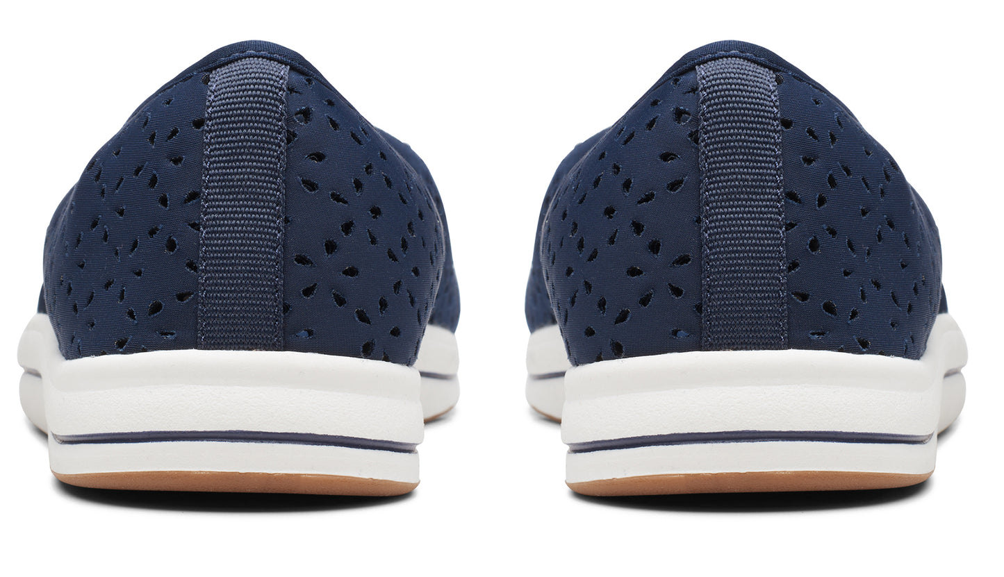 Rear view of a pair of dark blue perforated flats with white midsoles and brown outsoles.