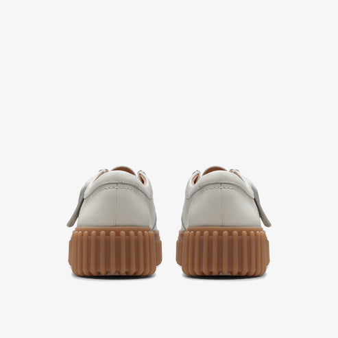 Pair of white casual shoes with thick brown treaded soles, shown from the back.