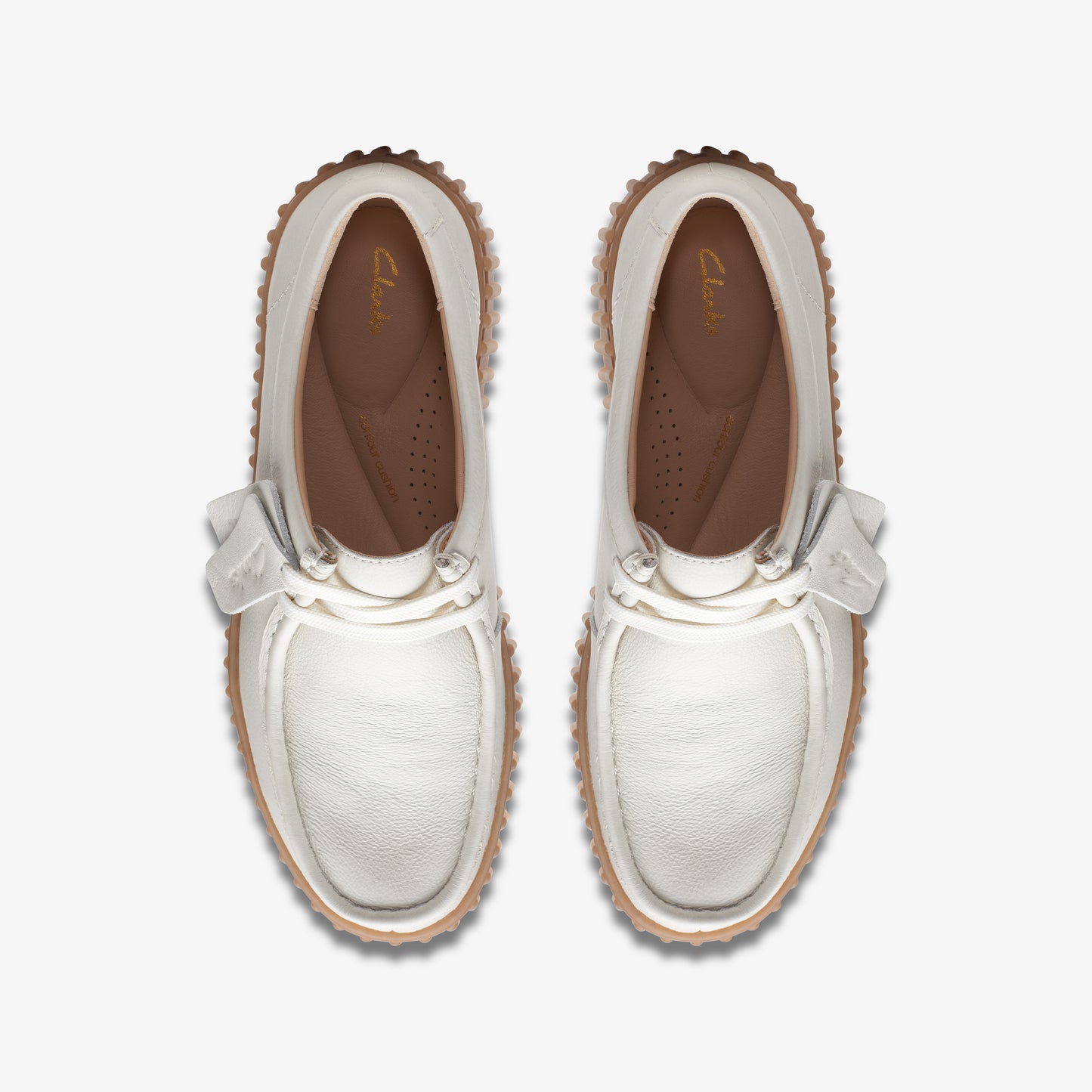 Top-down view of two white moccasin shoes with a ribbon tie.