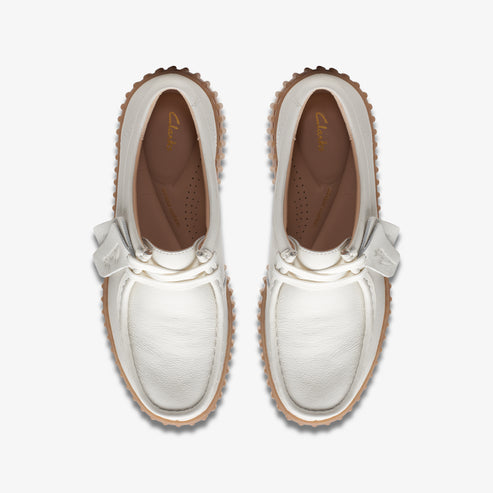 Top-down view of two white moccasin shoes with a ribbon tie.