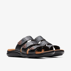 A pair of black leather sandals with laser-cut details and brown accents.