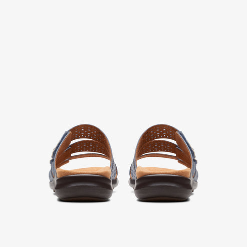 Back view of two blue denim sandals with brown soles and laser cut details.
