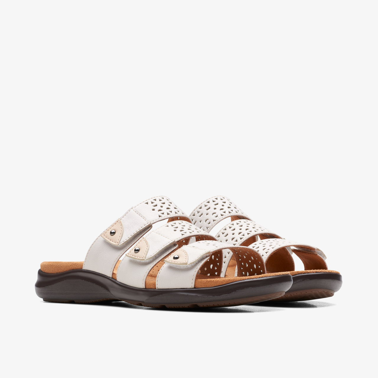 White slide sandals with laser-cut accents and adjustable straps.