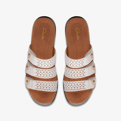 Top-down view of white leather sandals with decorative cutouts and three straps.