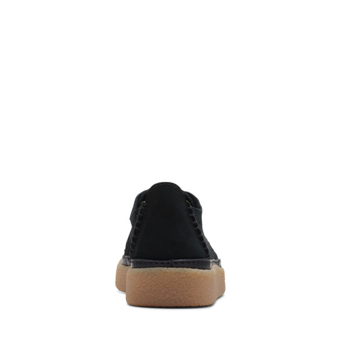 Low-profile black suede shoe with beige sole, viewed from the back.