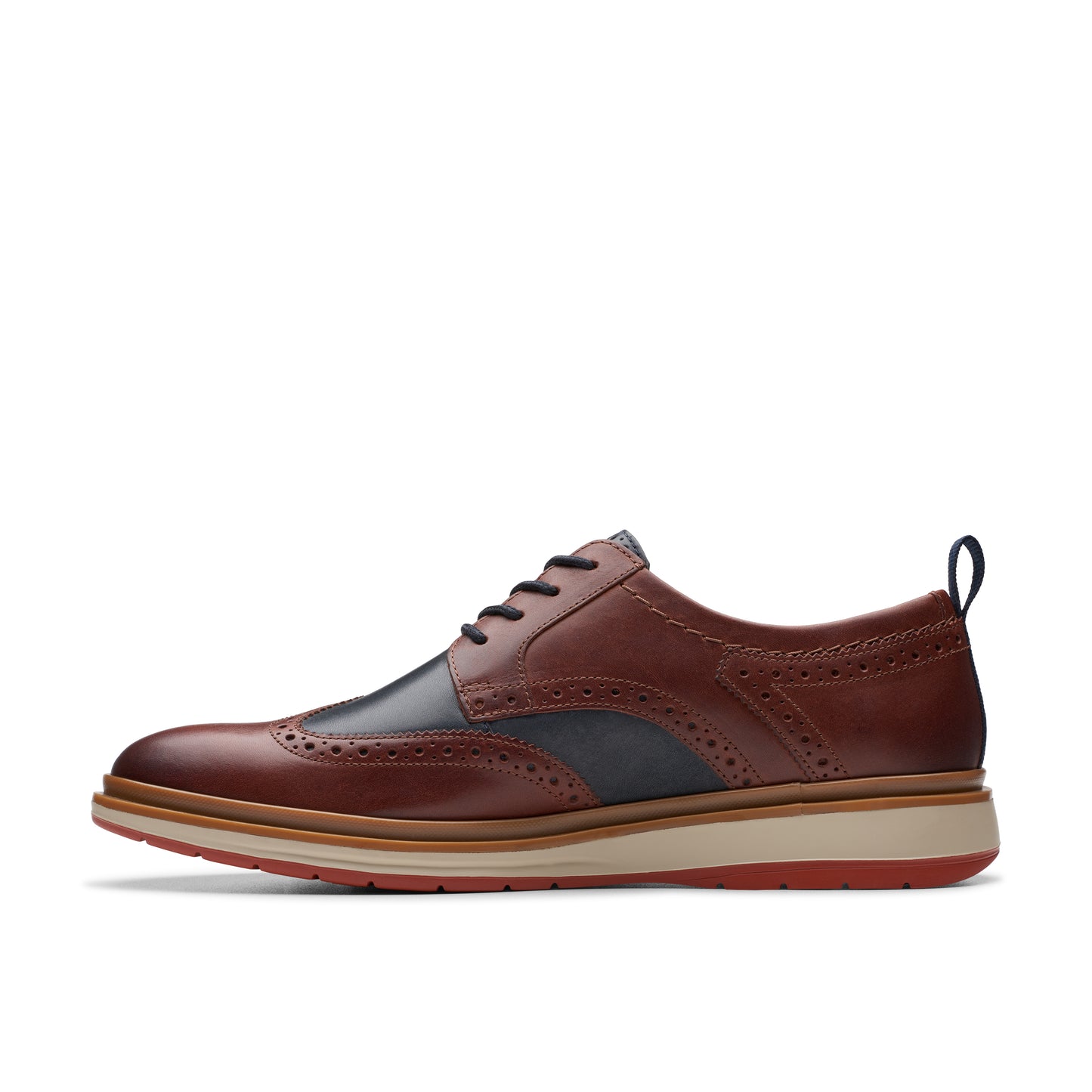 Side view of a brown and black wingtip shoe with a red sole.