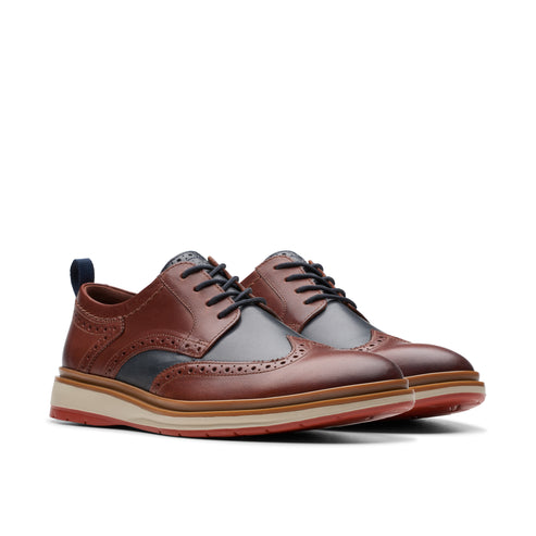 A pair of brown leather wingtip oxford shoes with a thick sole.