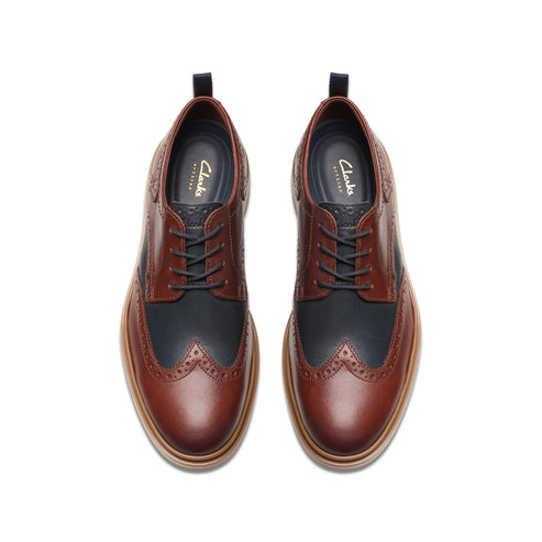 Top view of two leather dress shoes with wingtip brogue details; dark blue and dark brown.