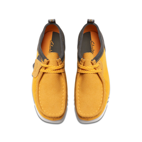 Overhead view of mustard-yellow nubuck shoes with off-white soles and dark-gray trim.