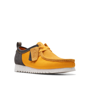A low cut shoe in gold and charcoal with a white sole and gold laces.