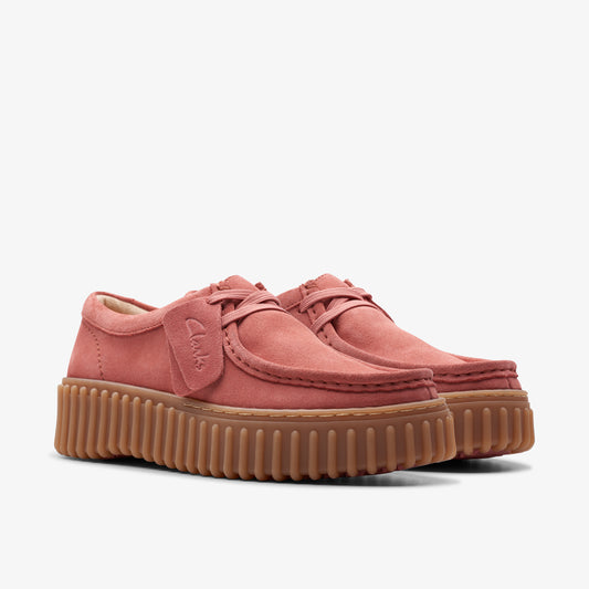 Coral-colored suede shoes with laces and a chunky, ridged brown sole.