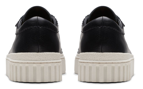 Rear view of pair of black leather sneakers with white ridged soles.