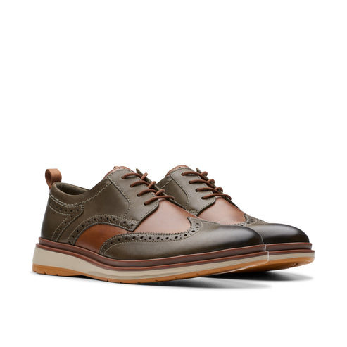 A pair of olive green and brown lace-up wingtip shoes with a beige sole.