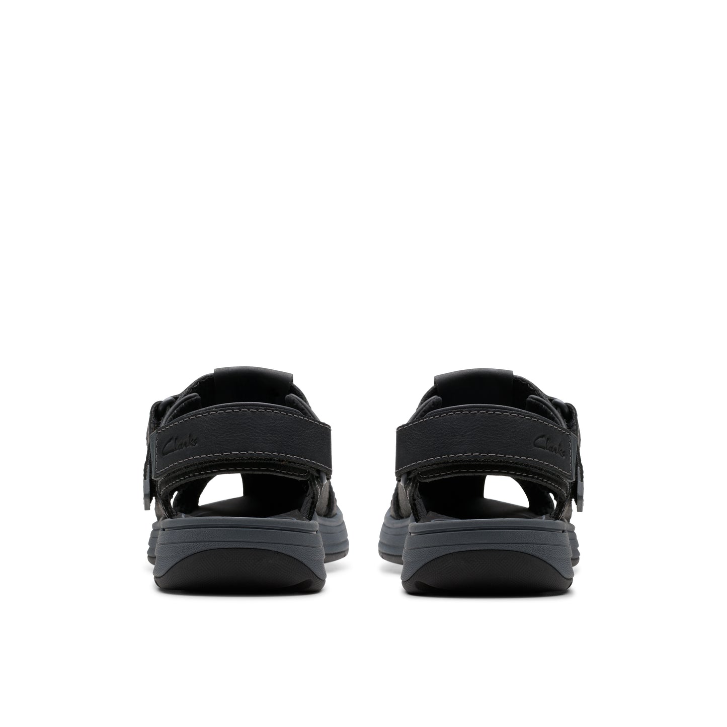 Rear view of two dark colored sandals with open top and velcro straps.
