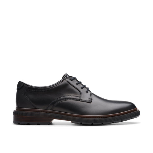 Black leather dress shoe with a lace-up closure and a flat, ridged sole.