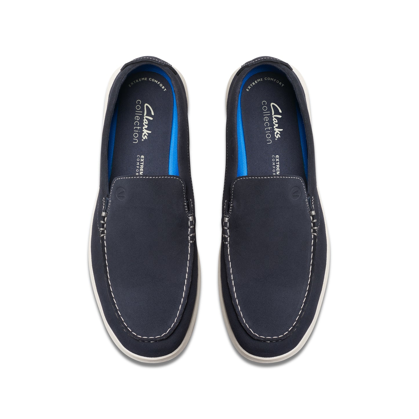 Overhead view of a pair of navy blue slip-on shoes with white soles and light blue inner lining. Visible text includes "Clarks Collection" and "EXTREME comfort".