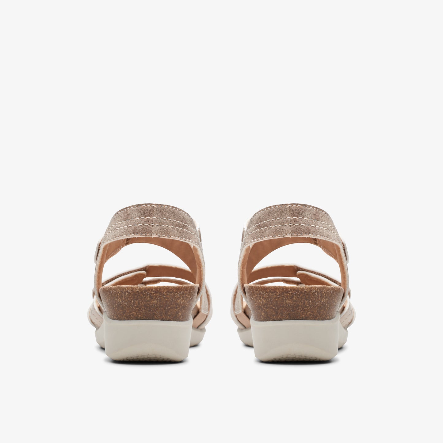 Rear view of two beige sandals with a cork wedge heel and adjustable heel strap.