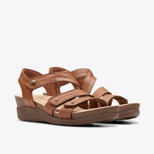 Pair of brown leather sandals with adjustable straps and low wedge heel.