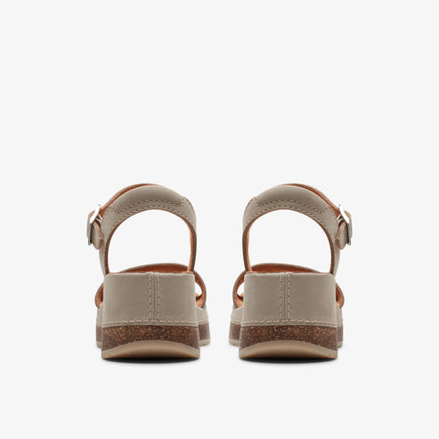 Pair of low heel, beige sandals with a buckled ankle strap, viewed from the back.