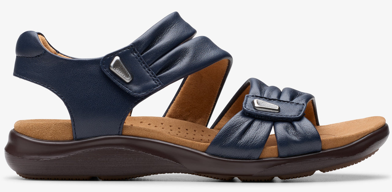 Navy blue sandal with ruched straps and a brown sole.
