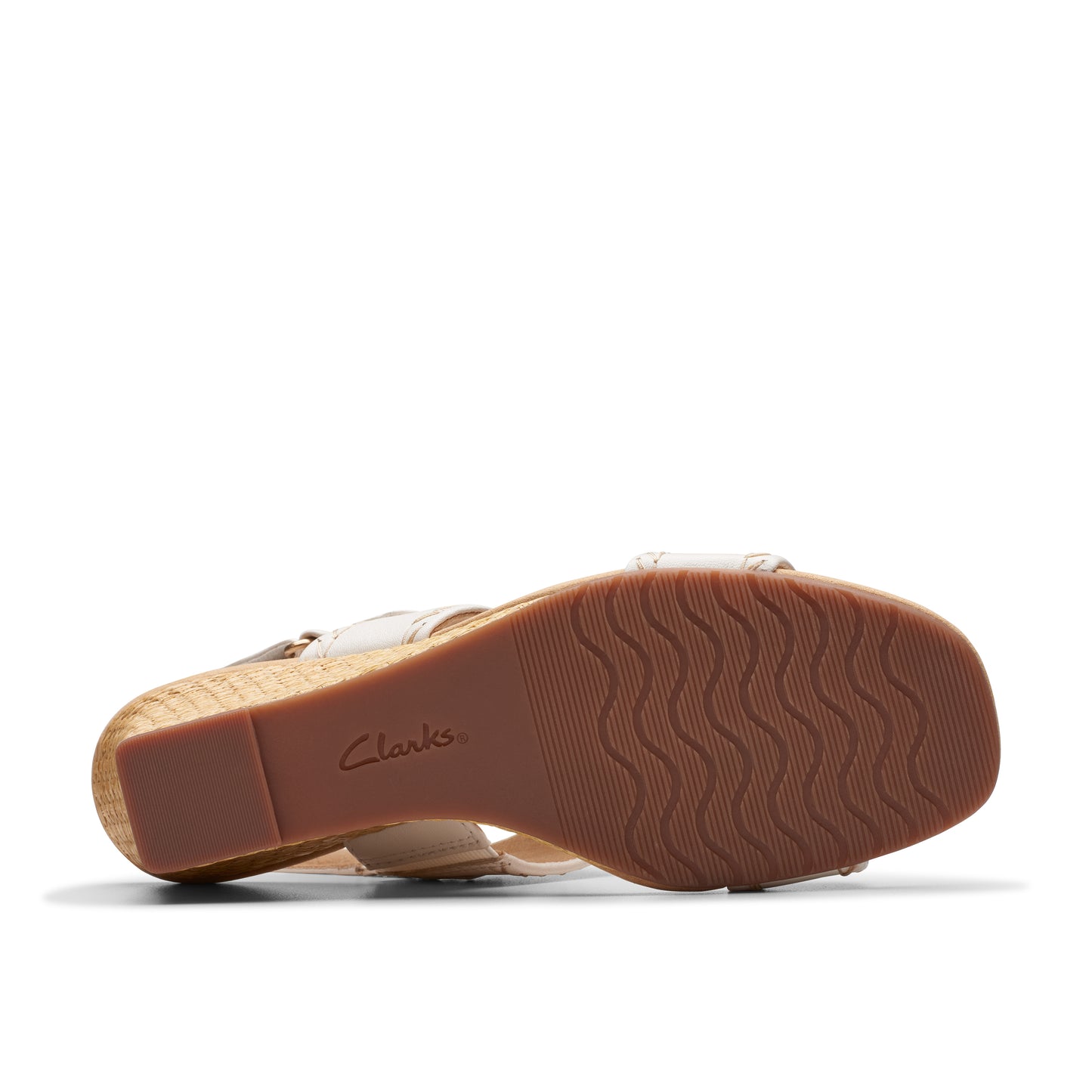 Bottom view of a cream colored sandal with cork wedge heel and treaded sole