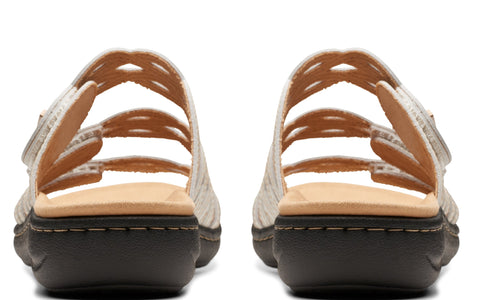 Pair of beige sandals with hook and loop fastener straps, low heel, rear view.