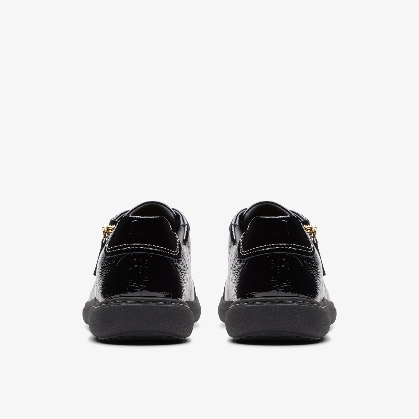 Back view of shiny black sneakers with gold zippers.
