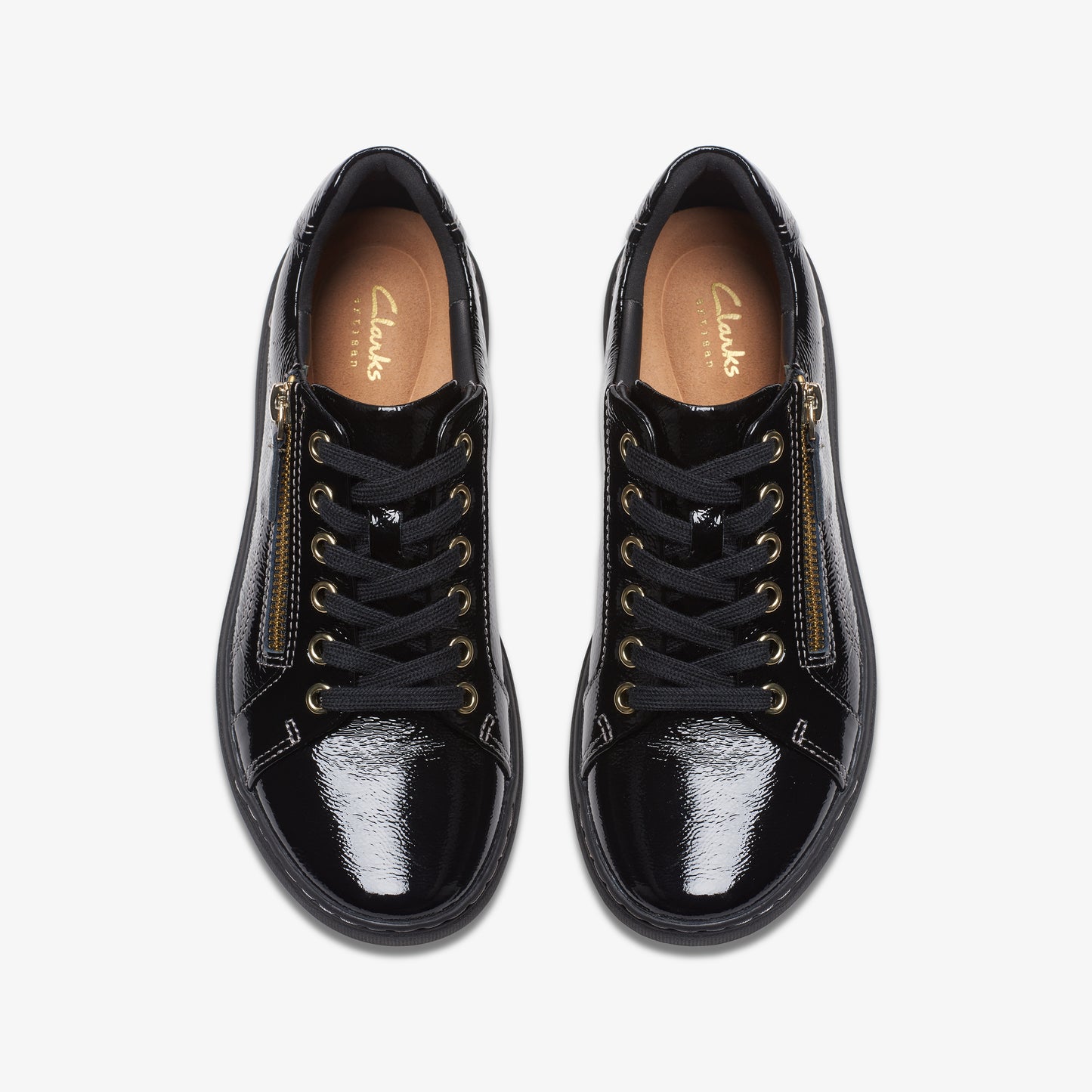 Top-down view of a pair of shiny black lace-up sneakers with gold zippers.