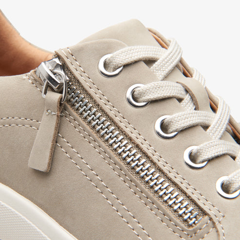 Closeup of a beige shoe with a zipper and laces.