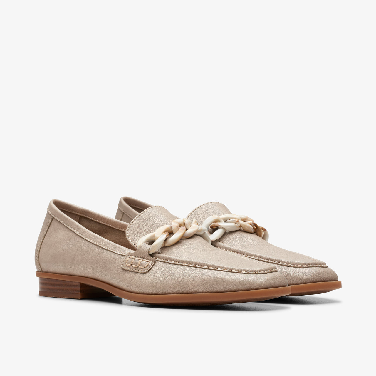 Pair of beige loafers with cream-colored decorative chain on top.