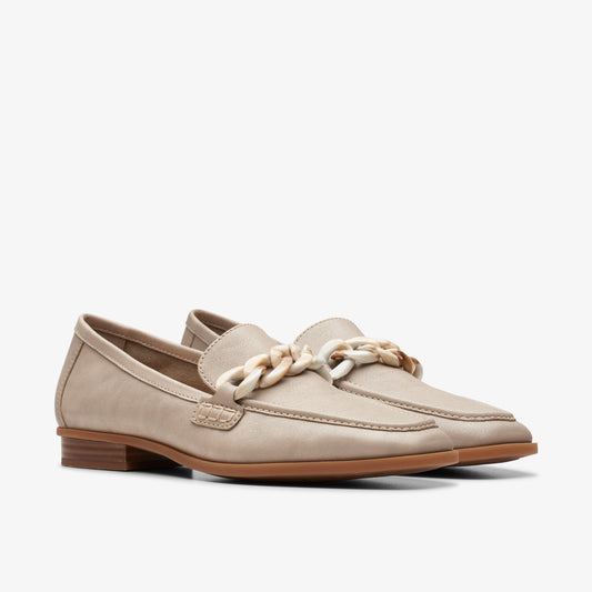 Pair of beige loafers with cream-colored decorative chain on top.
