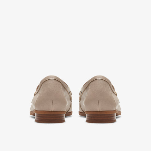A pair of closed-back taupe loafers with brown soles are viewed from behind.