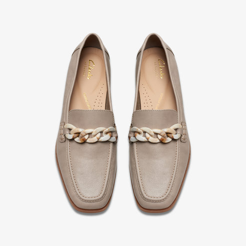 Pair of loafer shoes in light taupe with white chain detail.