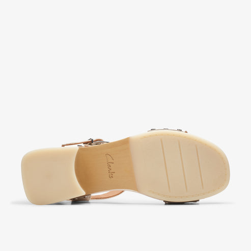 Bottom of a light-colored women's sandal showing its chunky heel and the brand name "Clarks" embossed in the middle.