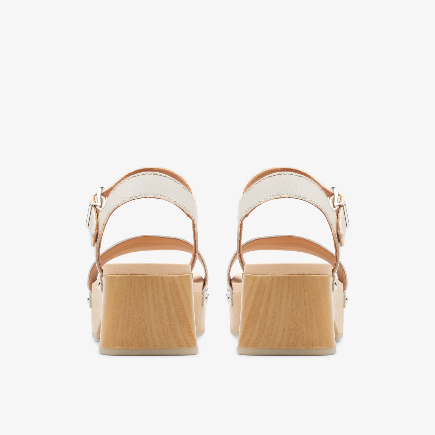 Back view of two high heel sandals with beige straps and light wooden block heels.