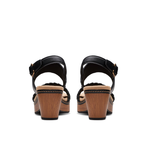 A pair of black chunky heels with wooden platform and braided detailing, viewed from the back.