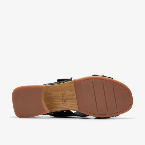 Bottom view of a sandal with a brown sole and light brown heel. The word 'Clarks' is embossed in the middle of the sole.