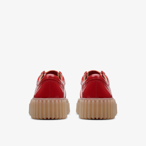 Rear view of two shiny red shoes with thick, tan-colored soles.