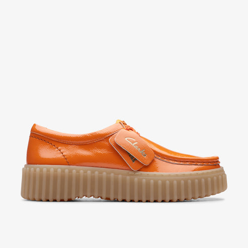 Orange patent leather moccasin with thick, ridged tan sole.