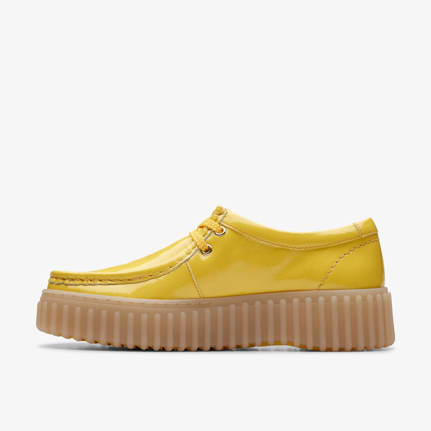 A side-view of a yellow patent leather low top shoe with rounded toe and a ribbed tan platform sole.