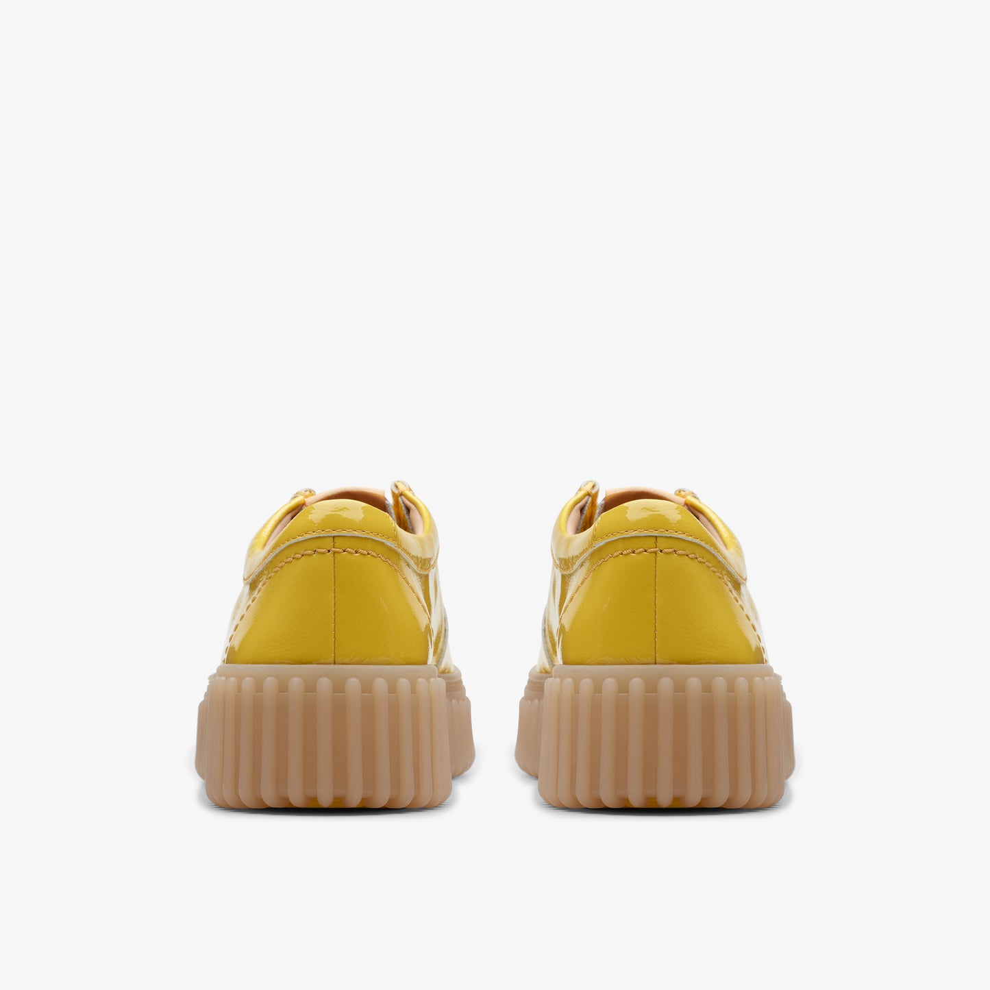 Two shiny yellow platform sneakers with ridged soles, viewed from the back.