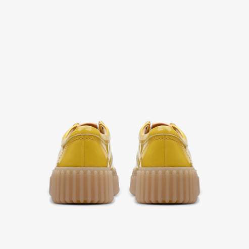 Two shiny yellow platform sneakers with ridged soles, viewed from the back.