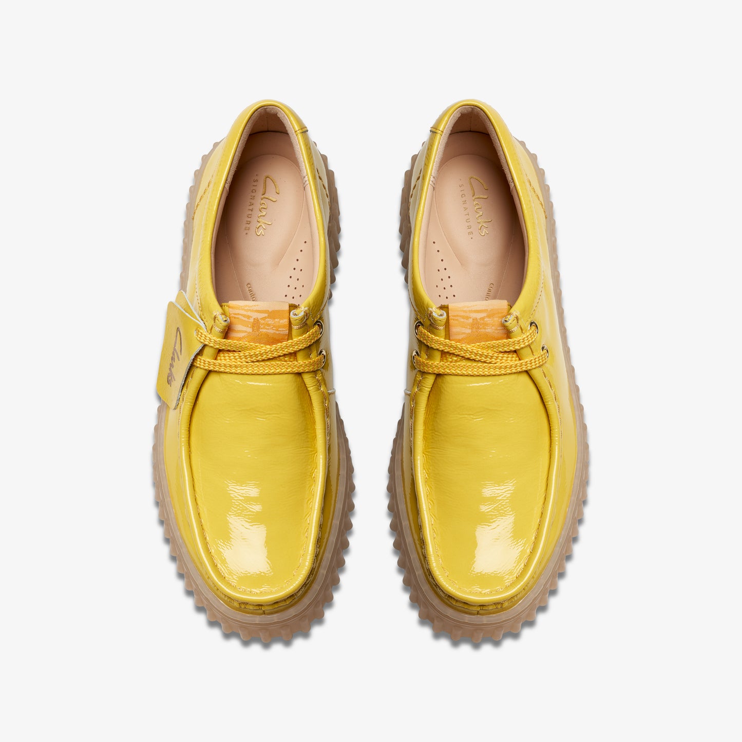Overhead view of pair of bright yellow, patent leather shoes with matching laces and light brown soles.