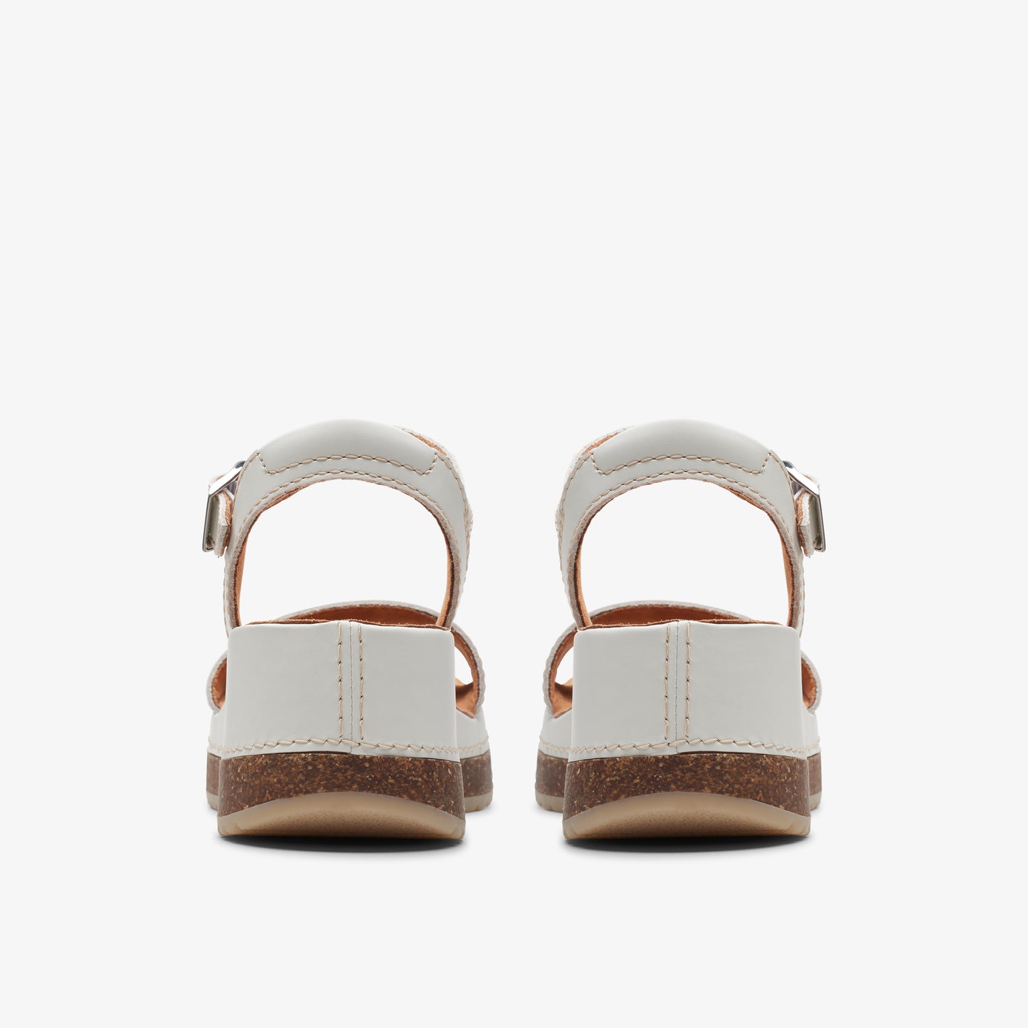 Pair of white sandals with adjustable buckle strap and cork soles.