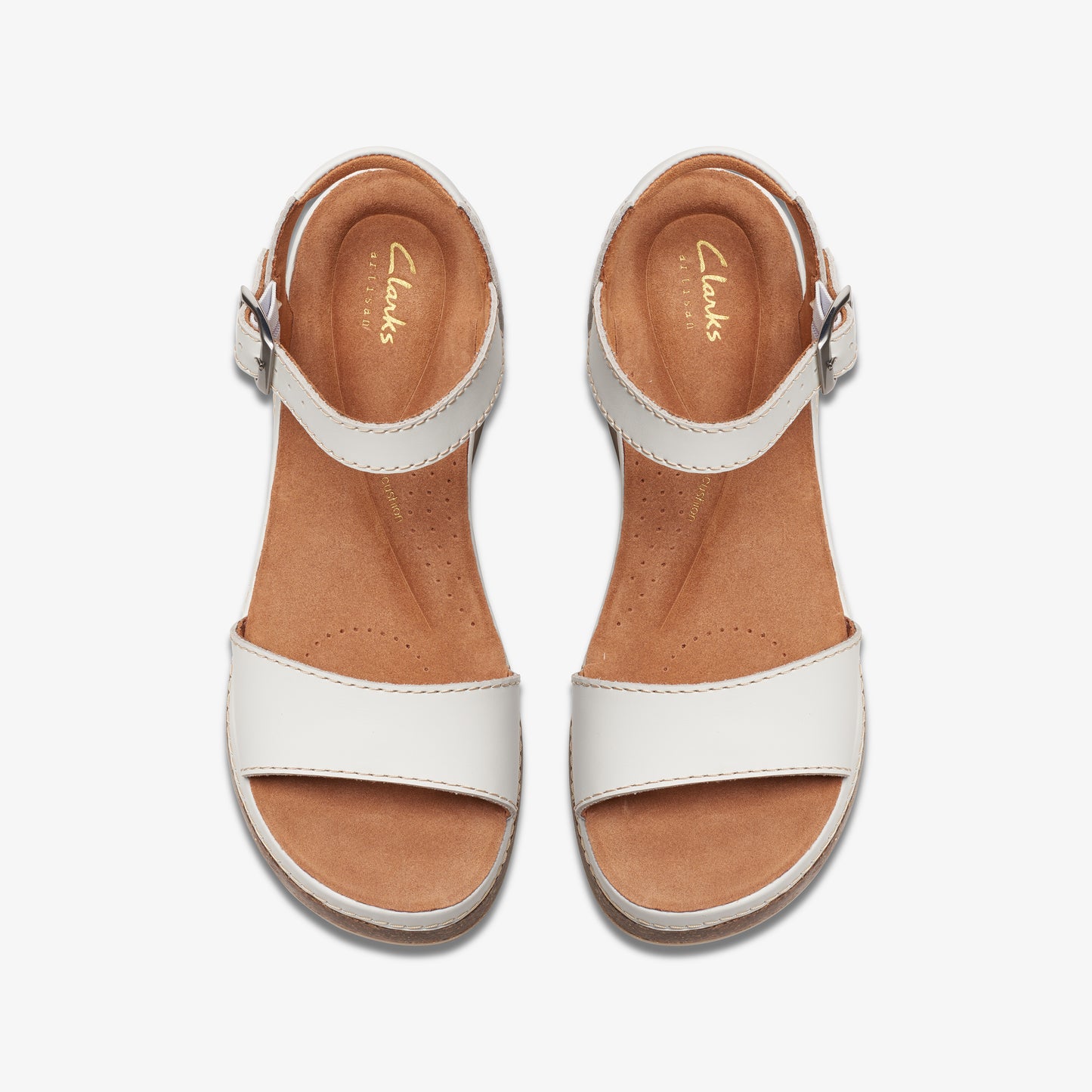 Top-down view of two identical white leather sandals with brown soles and silver buckles.