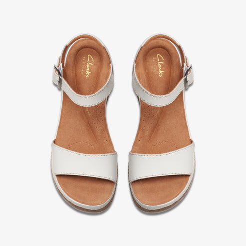 Top-down view of two identical white leather sandals with brown soles and silver buckles.