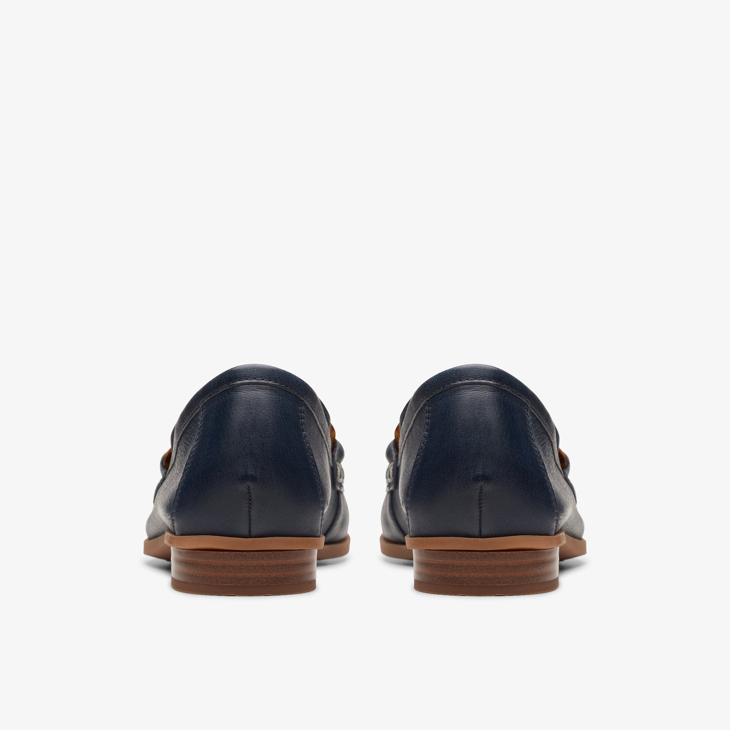 Rear view of a pair of navy loafers with a brown heel.