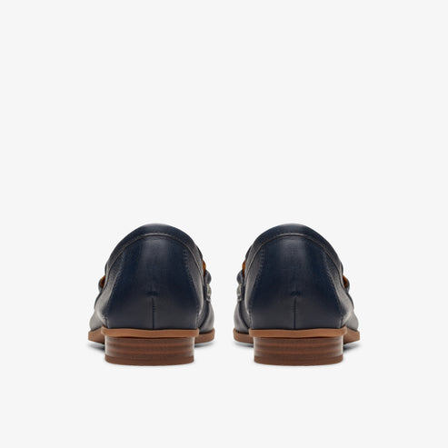 Rear view of a pair of navy loafers with a brown heel.