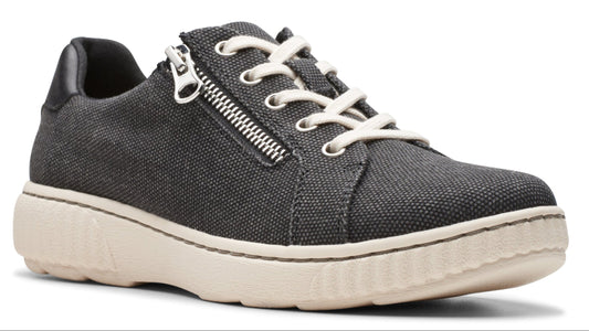 Black canvas sneaker with side zipper and white laces on a cream-colored sole.